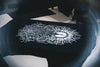 Screen printing process with a detailed black and white design on a black garment.