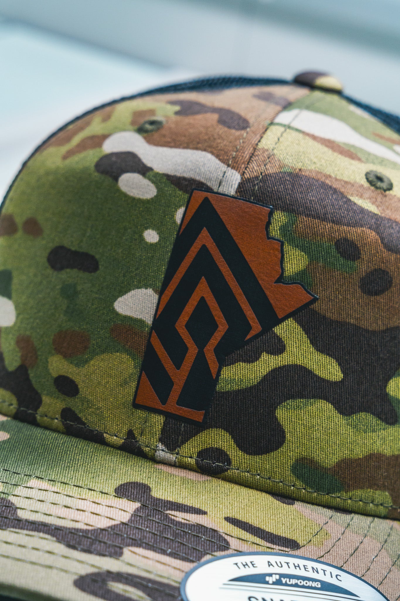 Camouflage snapback hat with custom laser engraved leather patch in the shape of Manitoba, produced in Winnipeg Manitoba Canada by Rogue Lab
